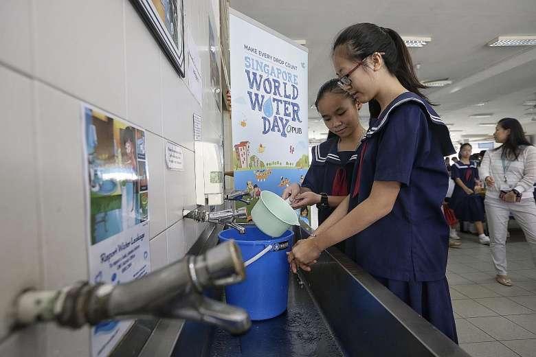 Secondary 2 students Chia Jia En (left) and Koh Wei Shan relying on water in a pail to wash their hands during the water rationing exercise at Woodgrove Secondary School yesterday. Woodgrove is the first of 45 schools, including pre-schools, to conduct the exercise this year.
